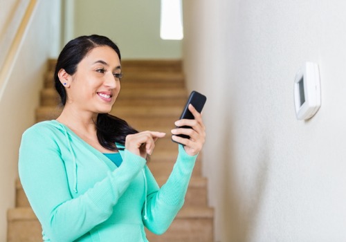 Woman Happily Adjusting Temperature from her Phone after Meeting with HVAC Contractors in Kirkwood MO