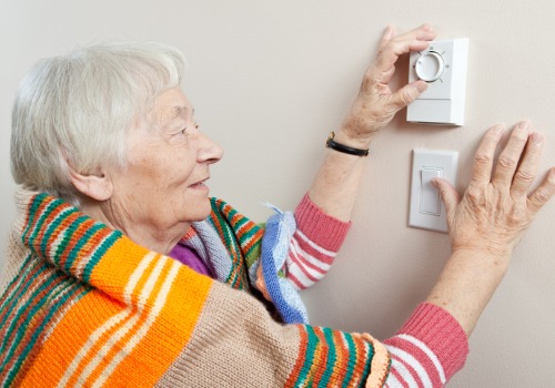 Elderly woman adjusting her thermostat after Furnace Repair in St. Louis MO
