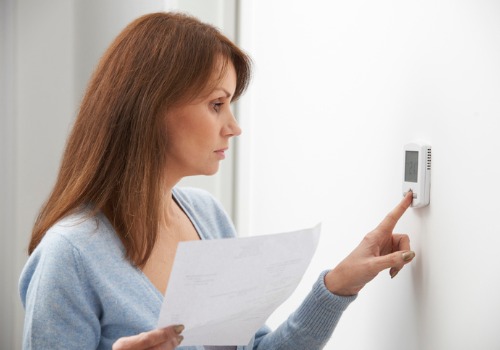 Woman Adjusting Thermostat of Residential Heating in the St. Louis MO area
