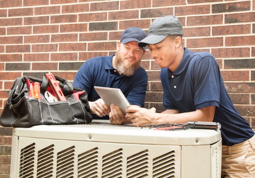 Repairman hard at work on an AC unit, providing residential air conditioning services in the St. Louis MO area