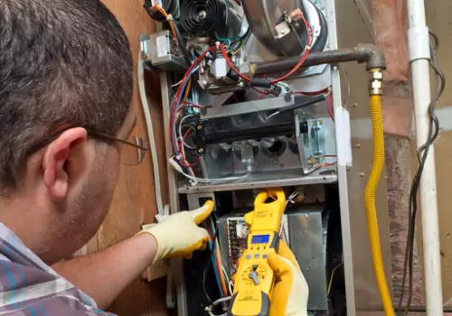A technician is seen working on a heating system. Xcell Williams Heating & Cooling offers heating repair.